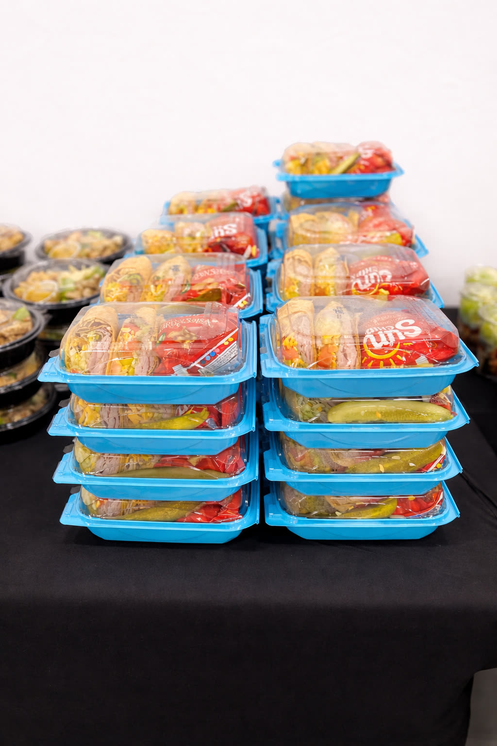 Stacks of KEYS boxed lunches with deli wraps, sides and Sun Chips, sealed and ready for delivery