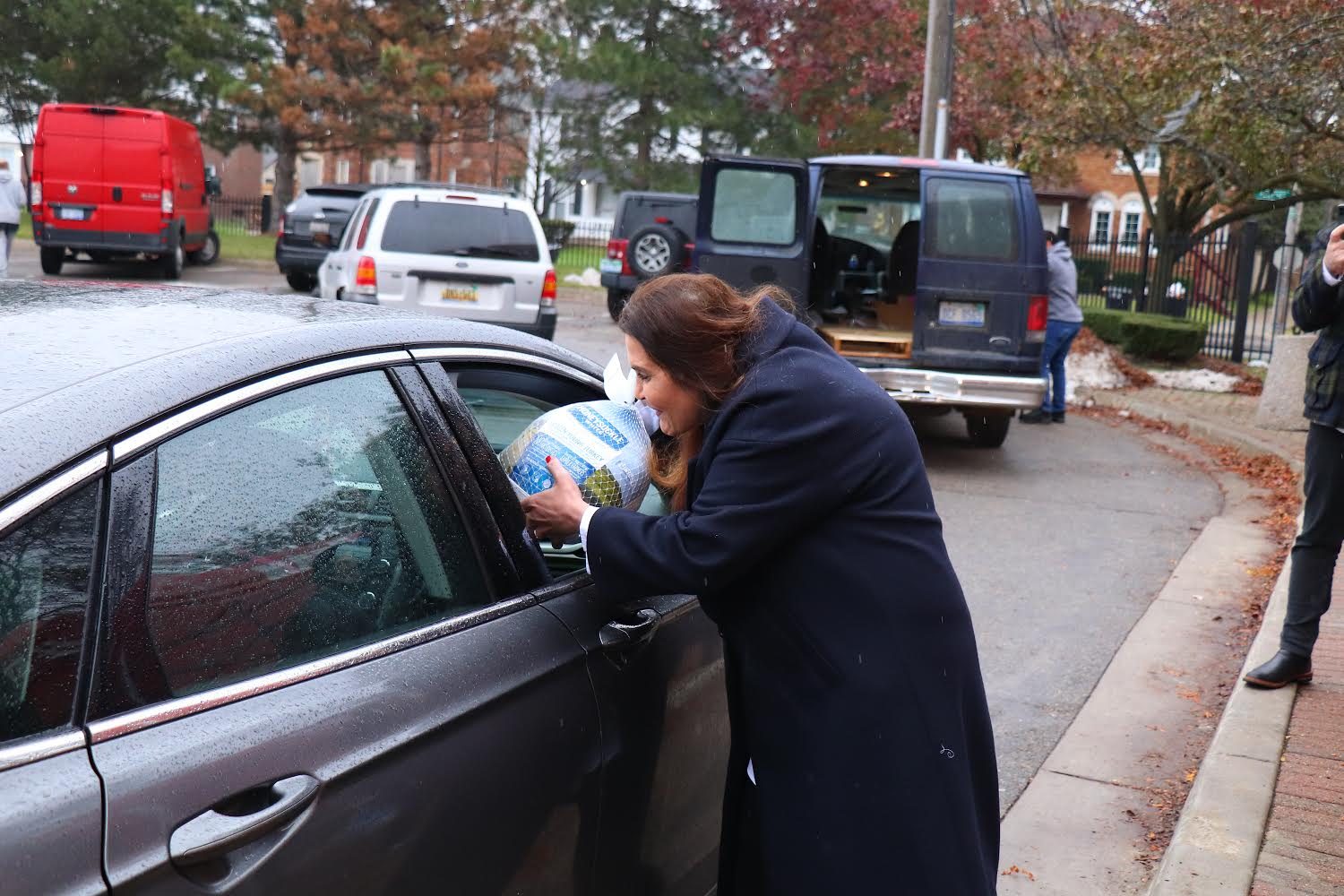 A KEYS volunteer hands a Thanksgiving turkey through the open window of a car at the Lorraine Commissary drive-through distribution