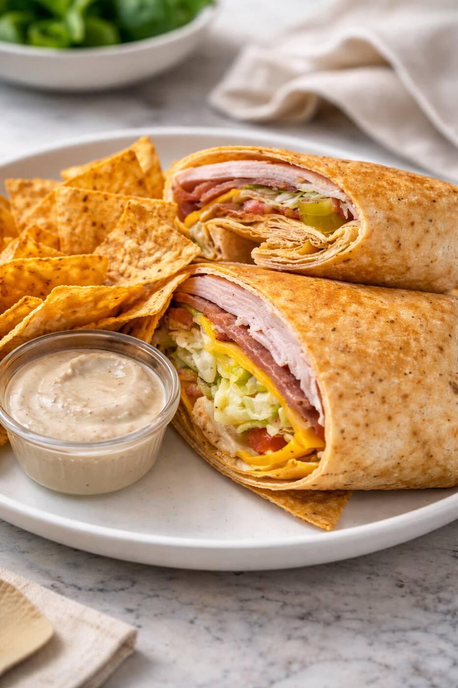KEYS turkey, ham and cheddar wrap halved on a plate with tortilla chips and a side of chipotle ranch